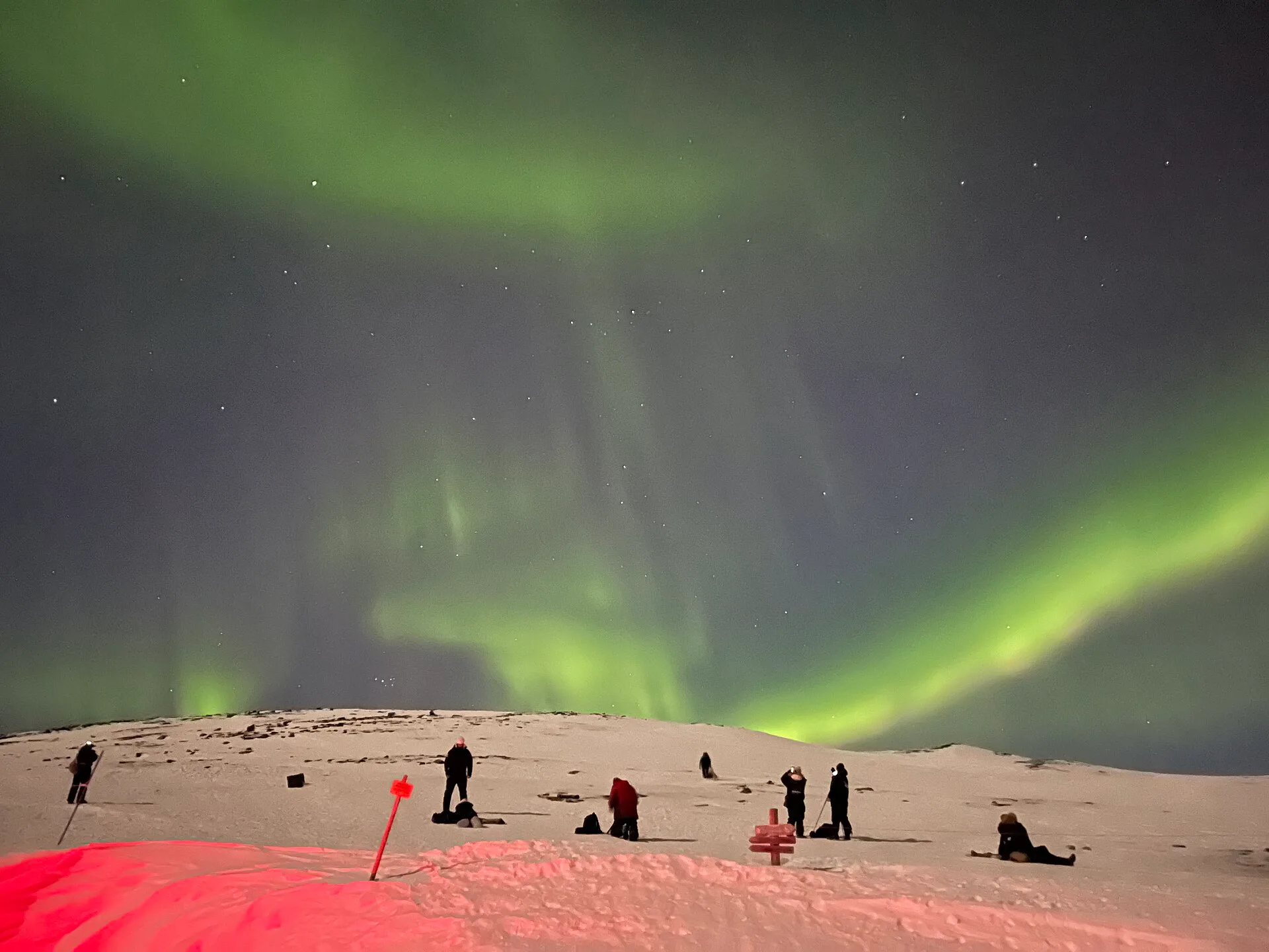 Personas fotografiando la aurora boreal desde una ladera nevada en Abisko