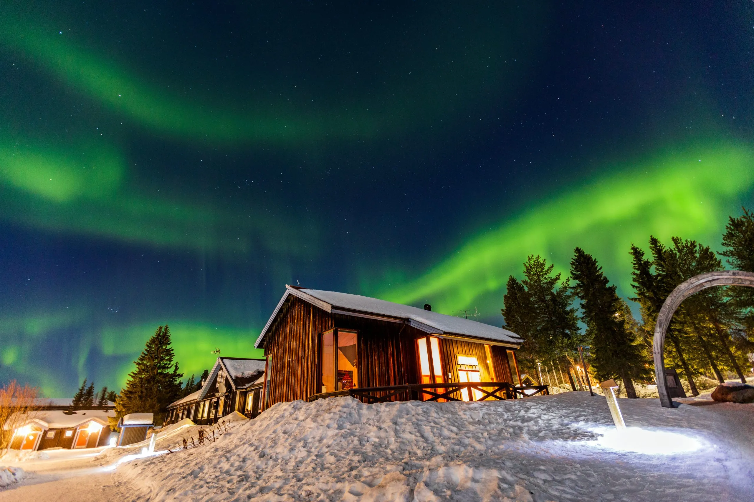 Aurora boreal sobre una cabaña de madera en Abisko, Laponia