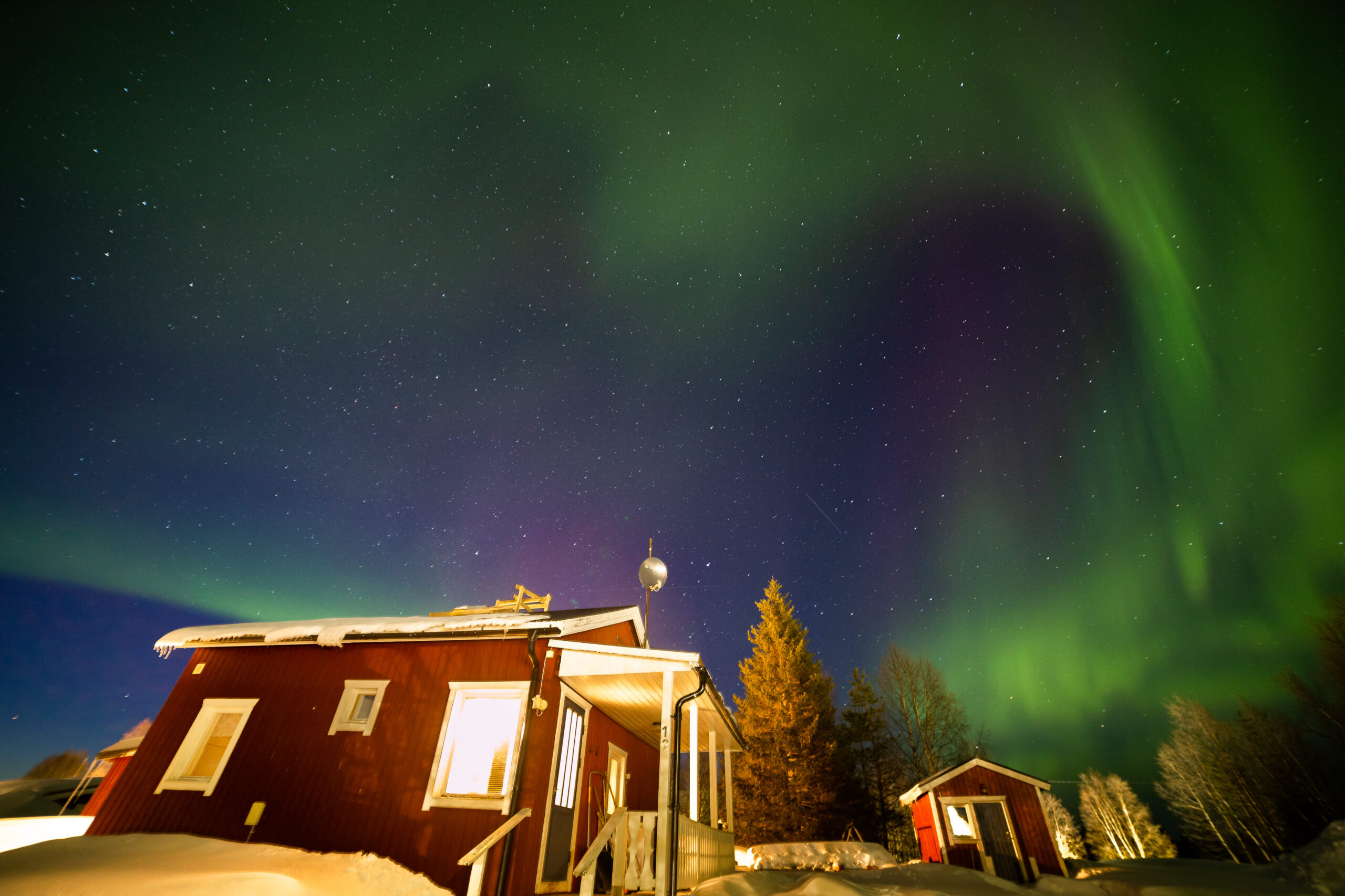 Aurora boreal verde sobre una cabaña roja tradicional sueca